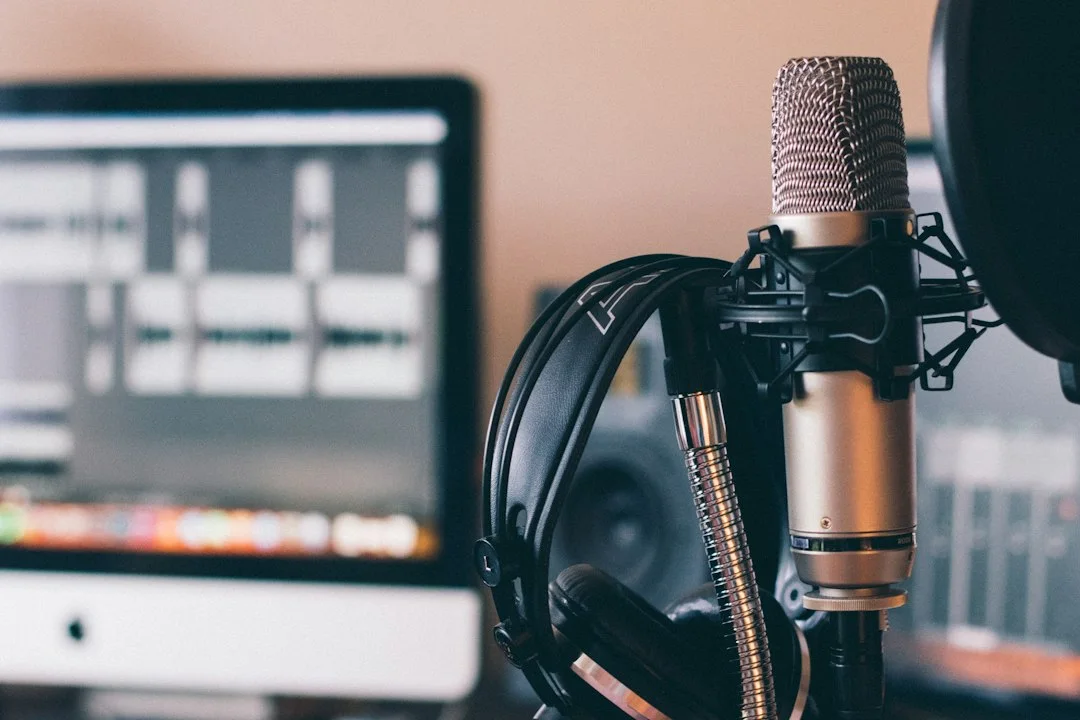 Microphone and headphones beside an audio editing screen.