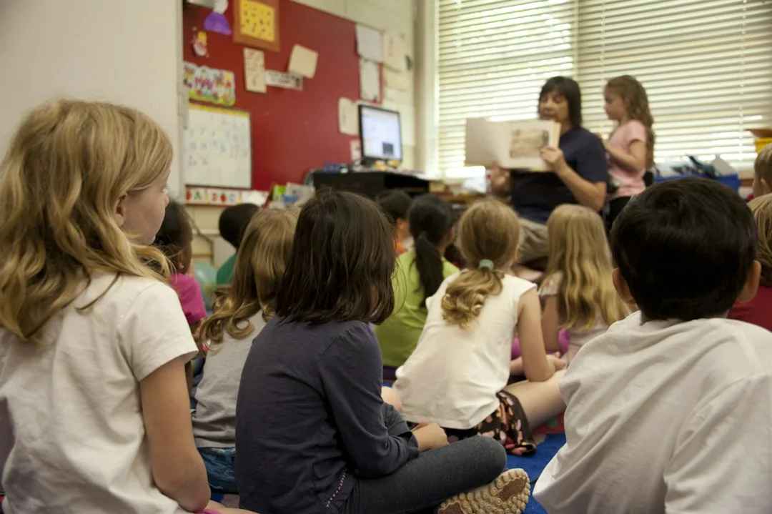 Children listening to a teacher read a story.