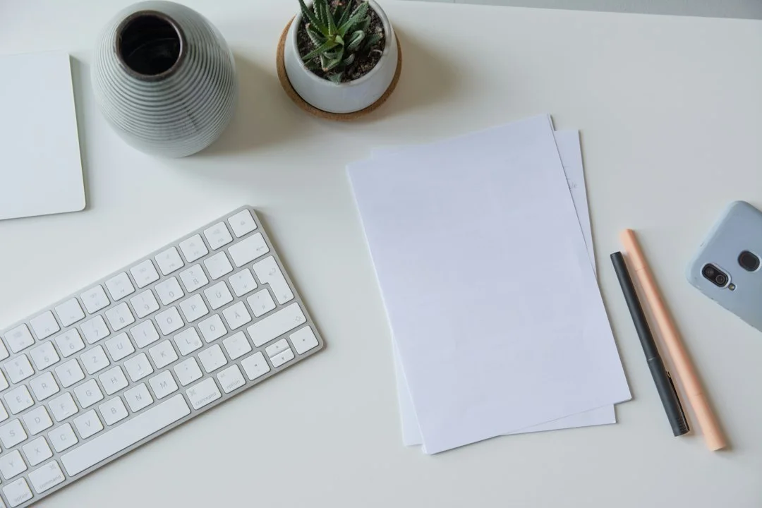 Blank pages and a keyboard on a work surface.