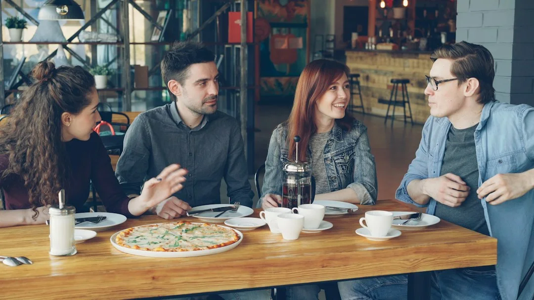 Friends sharing a conversation at a cafe table.