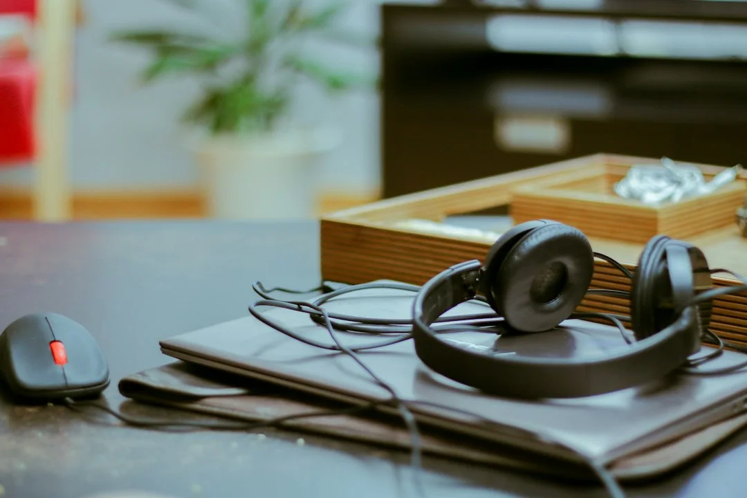 Headphones resting on a notebook beside a computer.