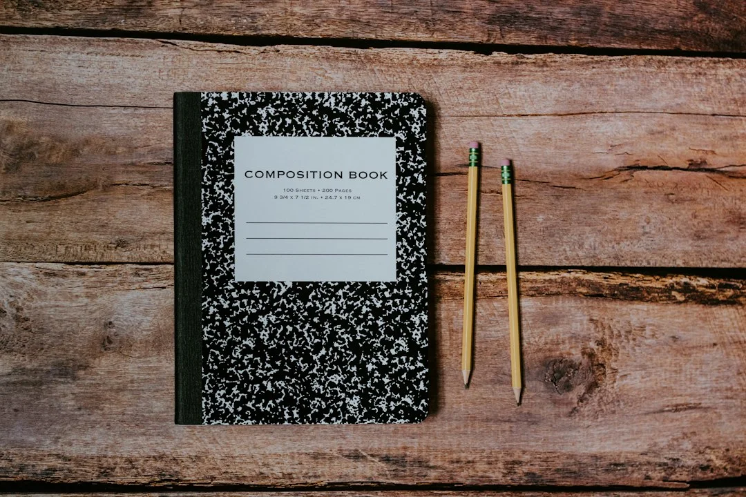A notebook and pencils on a wooden table.