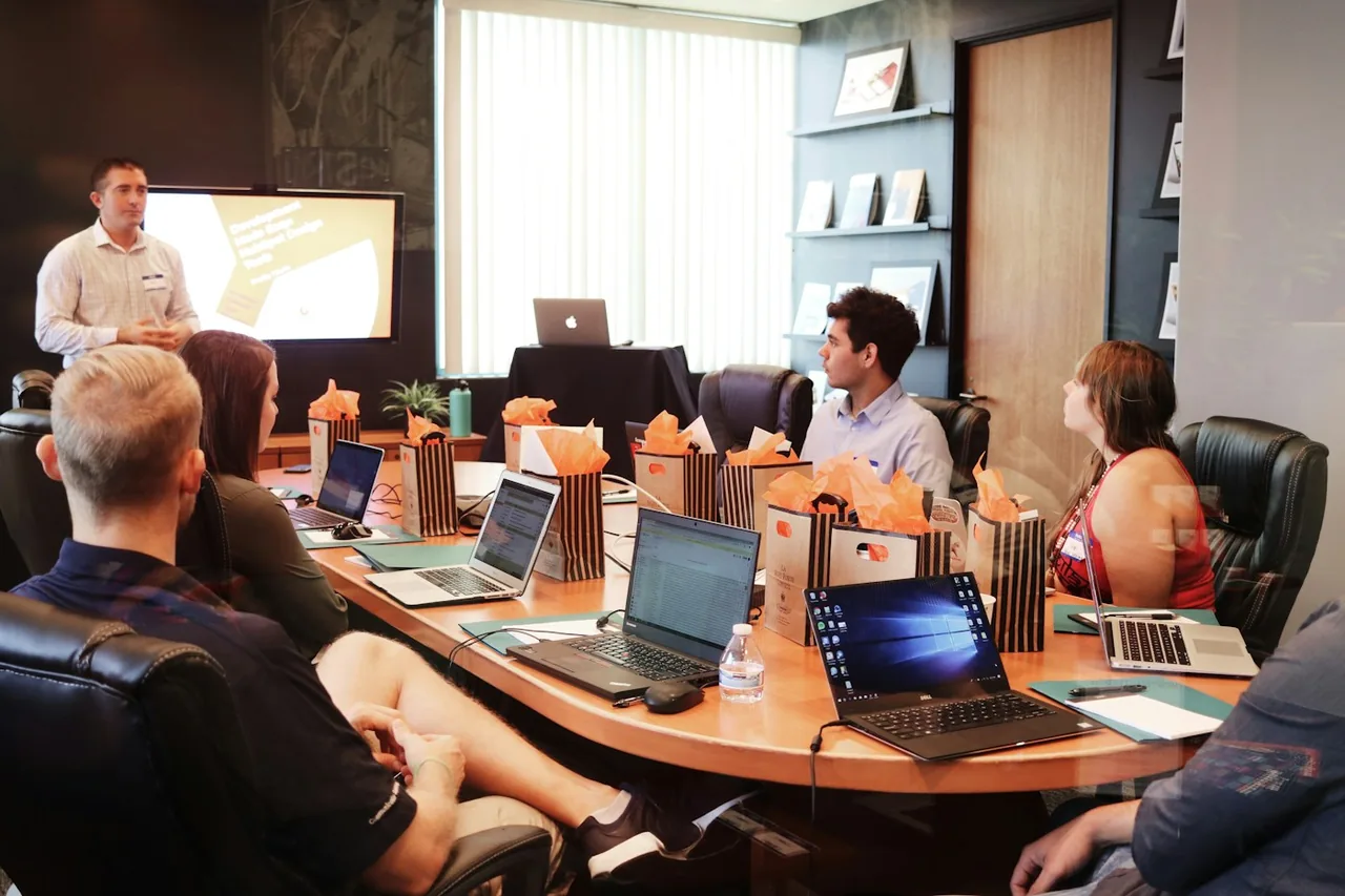 A presenter discussing a project with colleagues around a table.