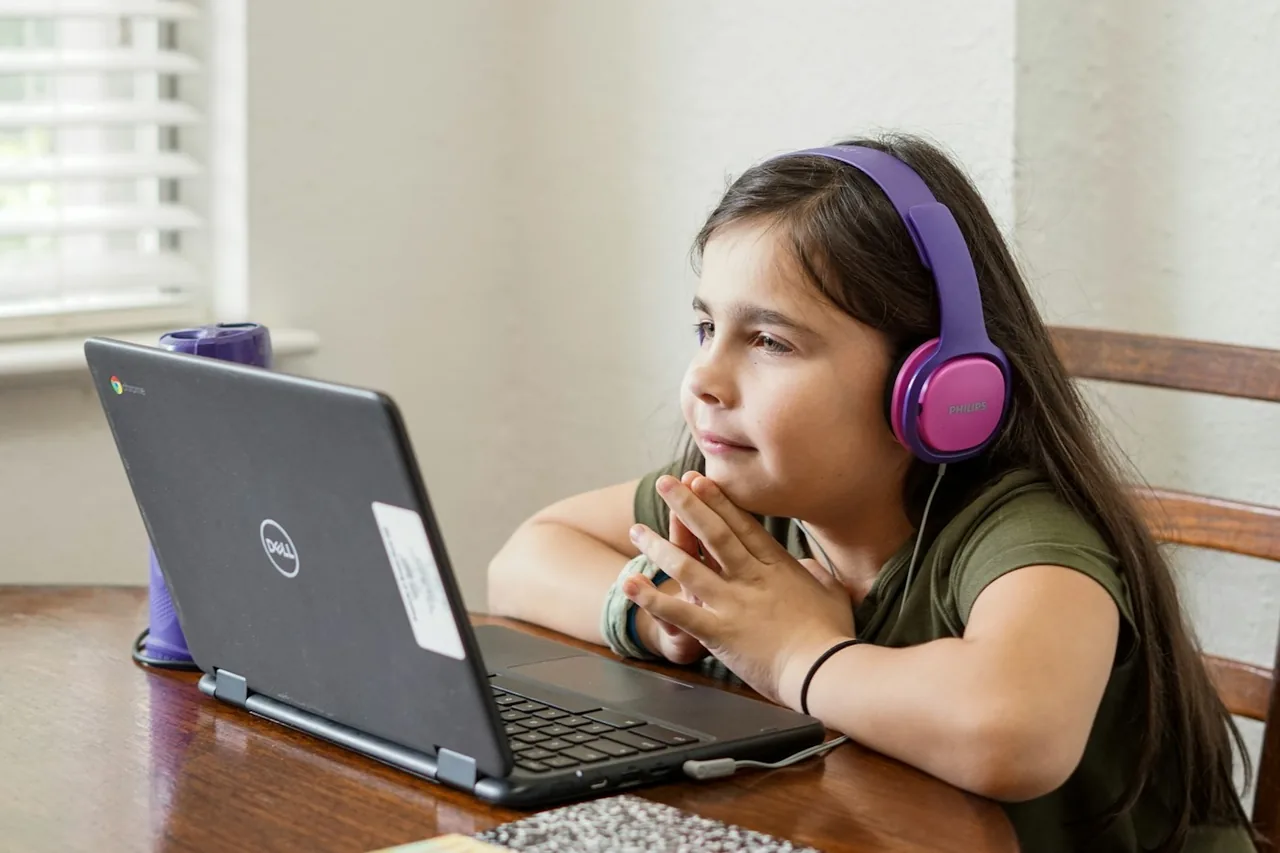 A child wearing headphones while using a laptop for remote learning.