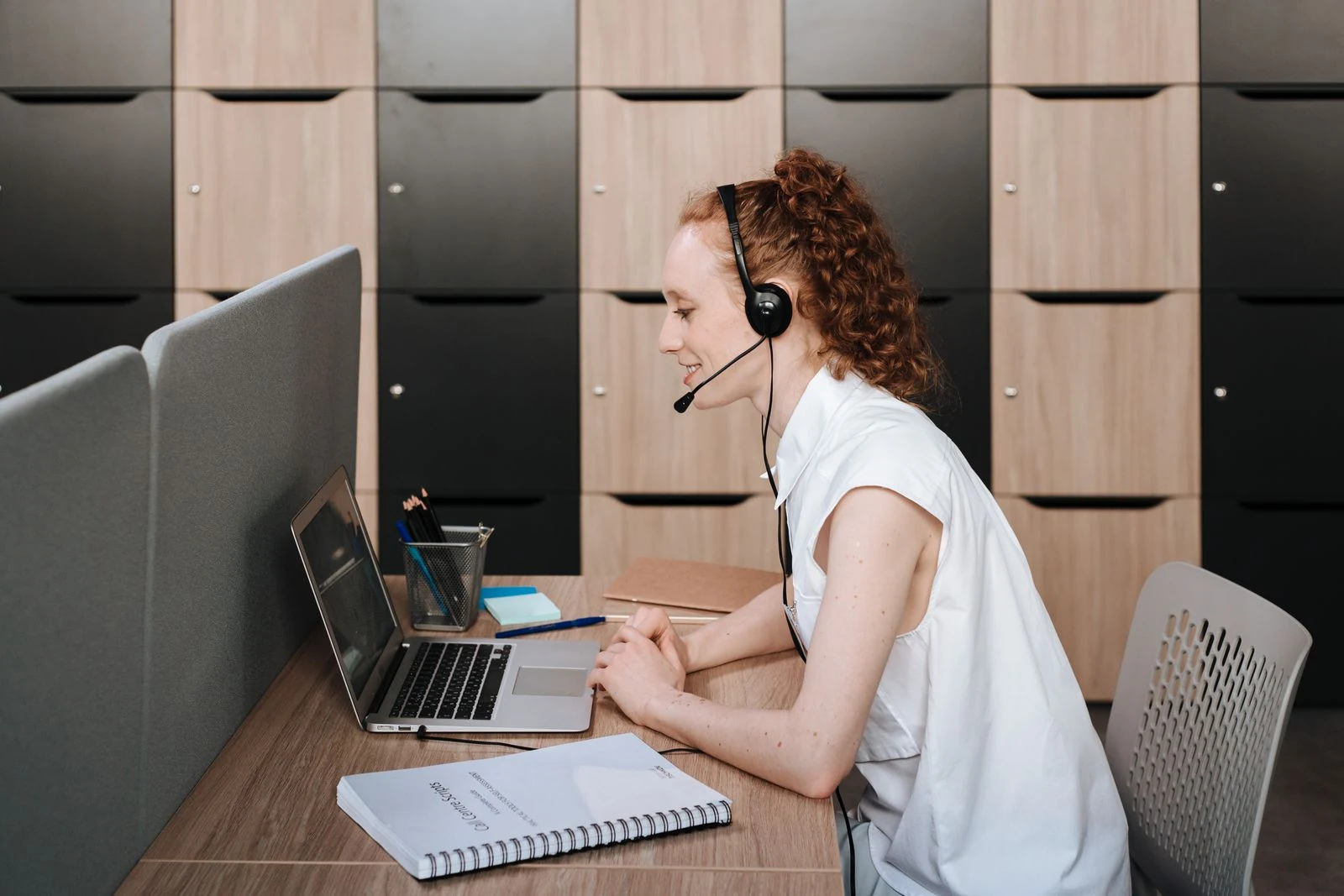 General American English — Stock photograph of a professional using a headset and laptop for a video call.