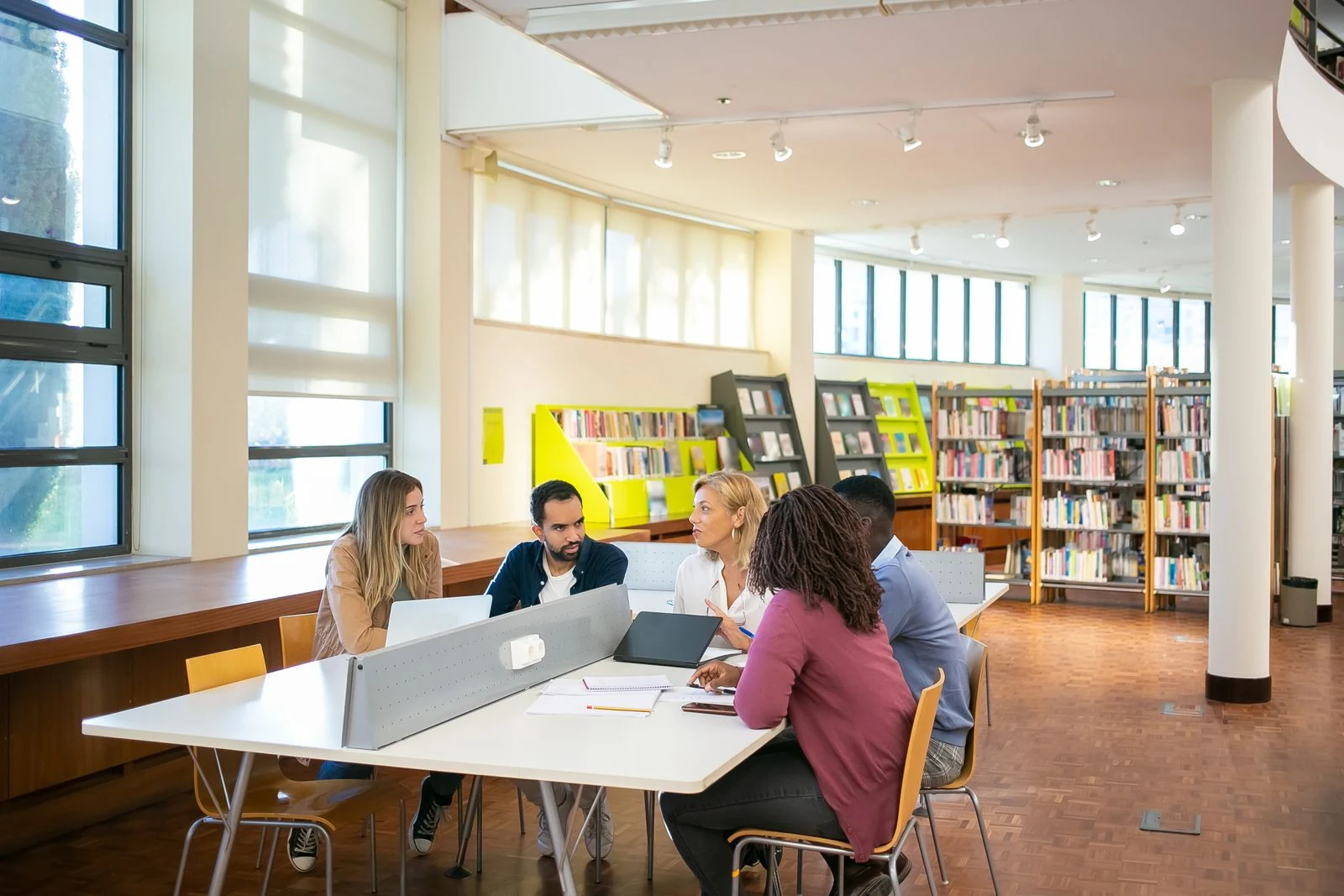 Stock photograph of adult learners working together at a laptop in a library.