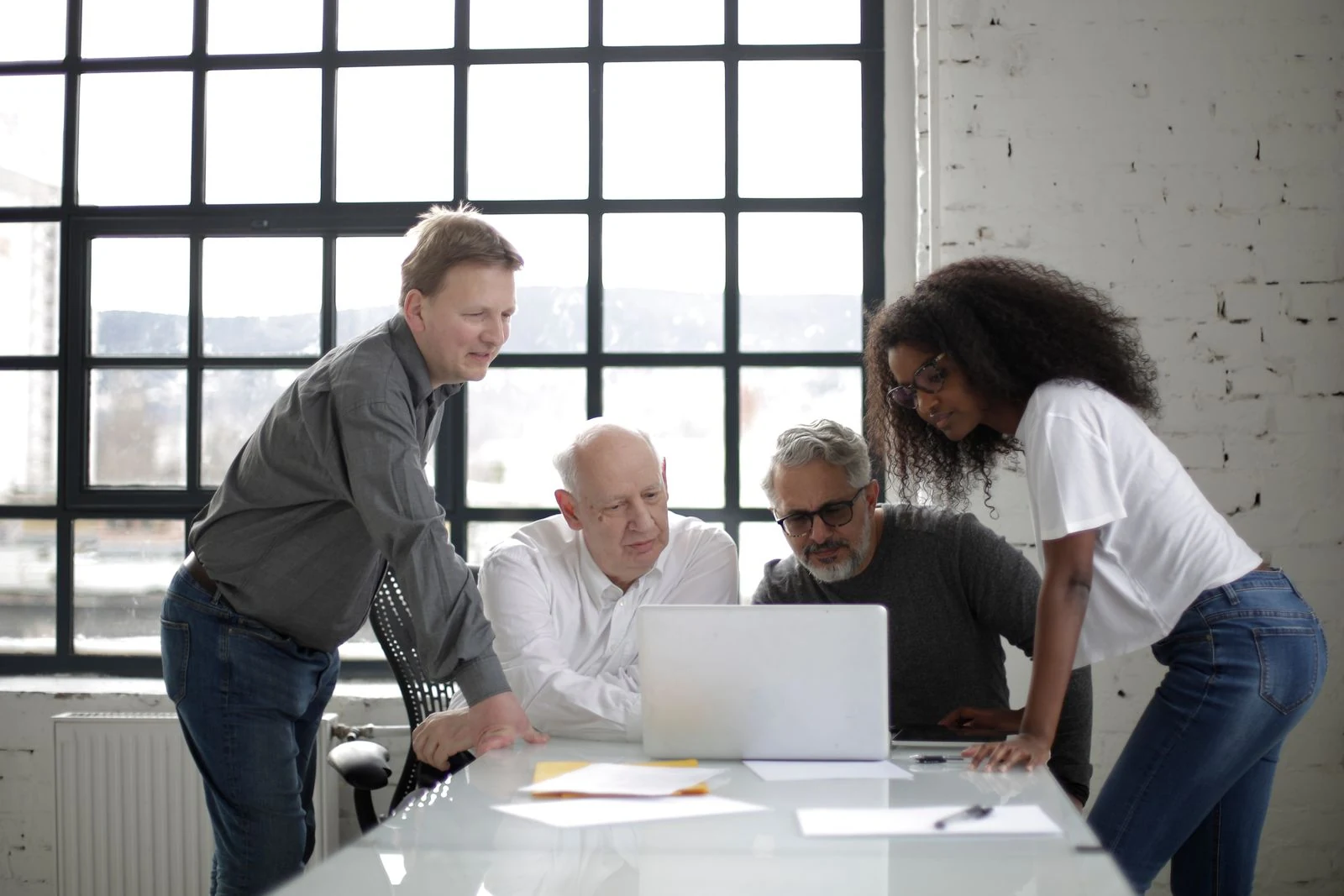 LSA GLOBAL — Stock photograph of colleagues collaborating around a laptop in a bright office.